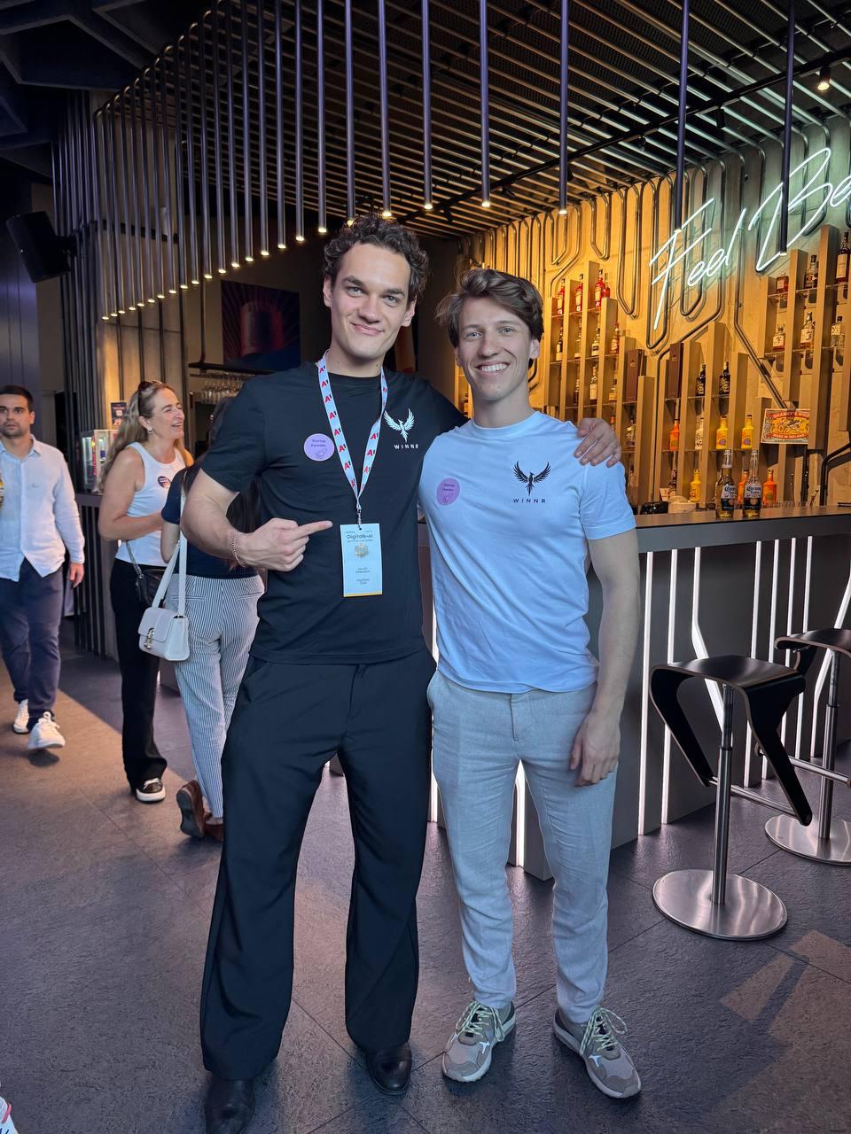 Two of the WINNR team side by side at an event, one with an arm around the other.